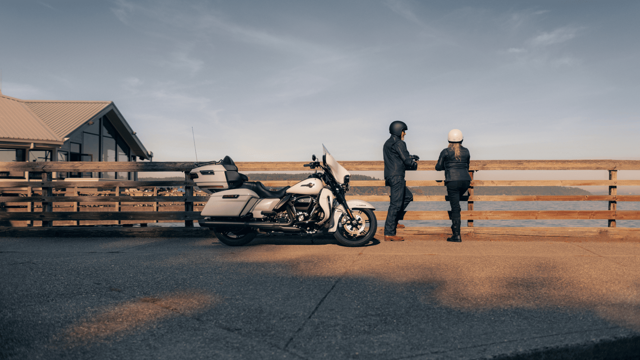 2024 Harley-Davidson® Ultra Limited® in sleek white parked on a scenic pier with two riders enjoying the view