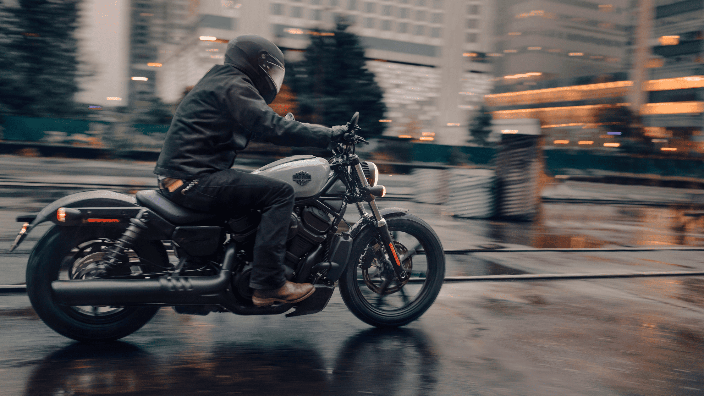 Rider accelerating on a 2025 H-D® Nightster® through a wet city street with blurred motion