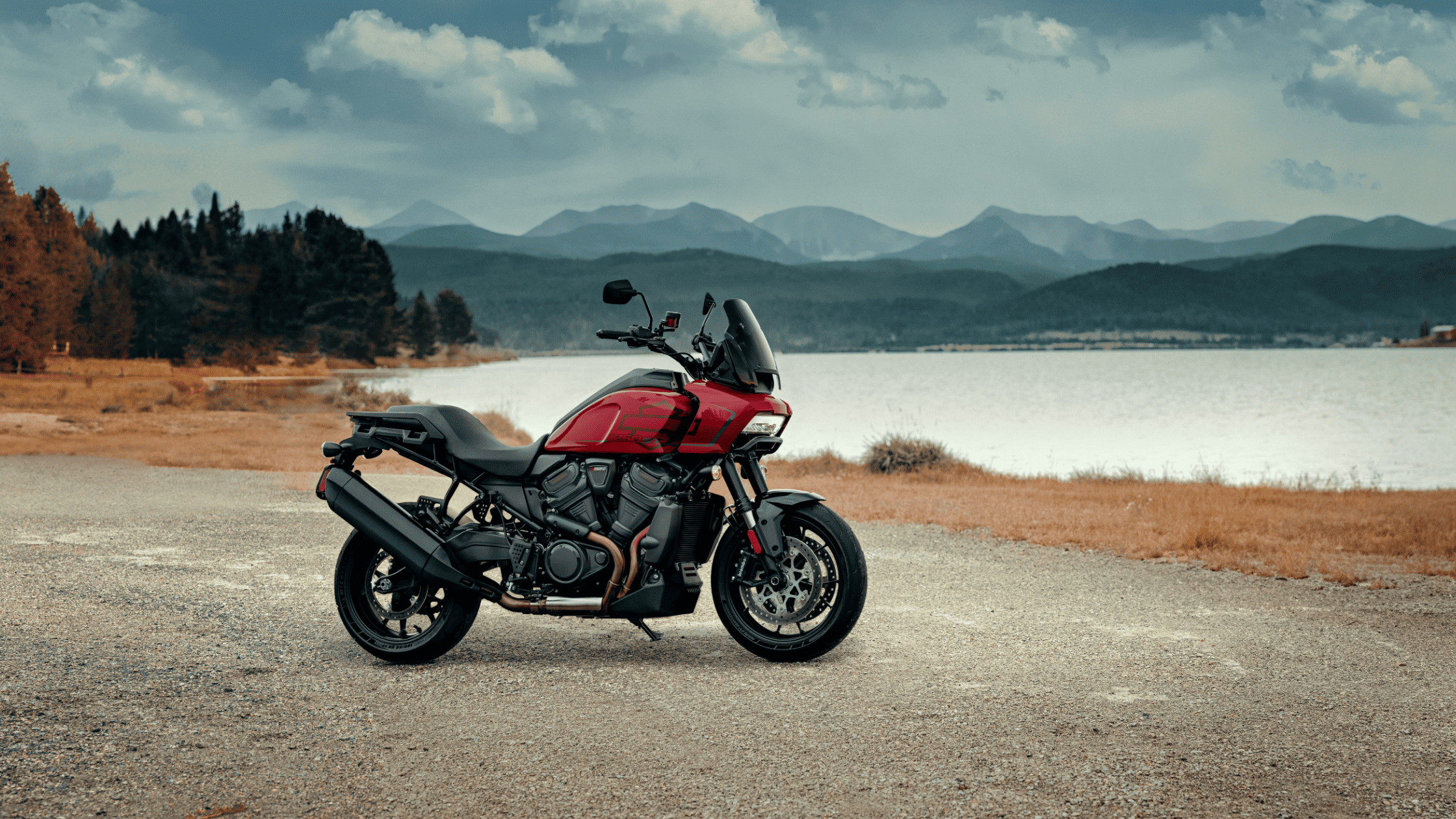 2025 H-D® Pan America® 1250 ST parked near a scenic lakeside with mountains in the distance