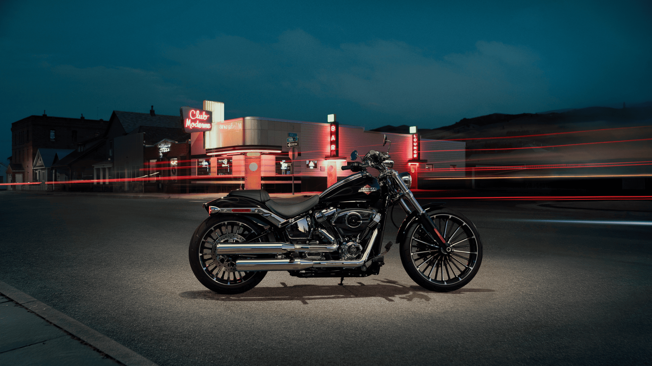 2025 Harley-Davidson® Breakout® parked at night near neon-lit Club Moderne on quiet street.