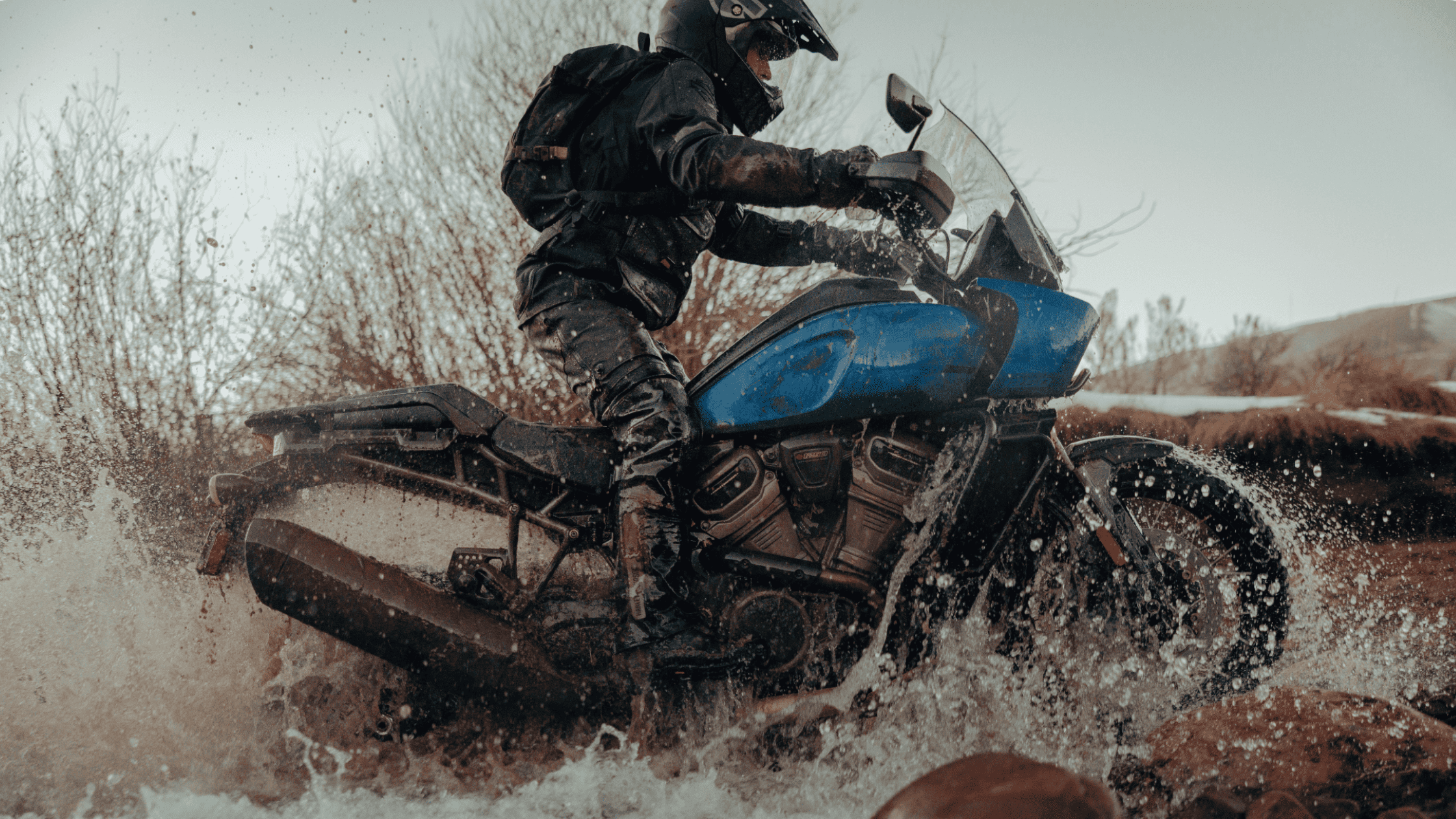 2025 Harley-Davidson® Pan America® 1250 Special off-road motorcycle splashing through muddy water tr…