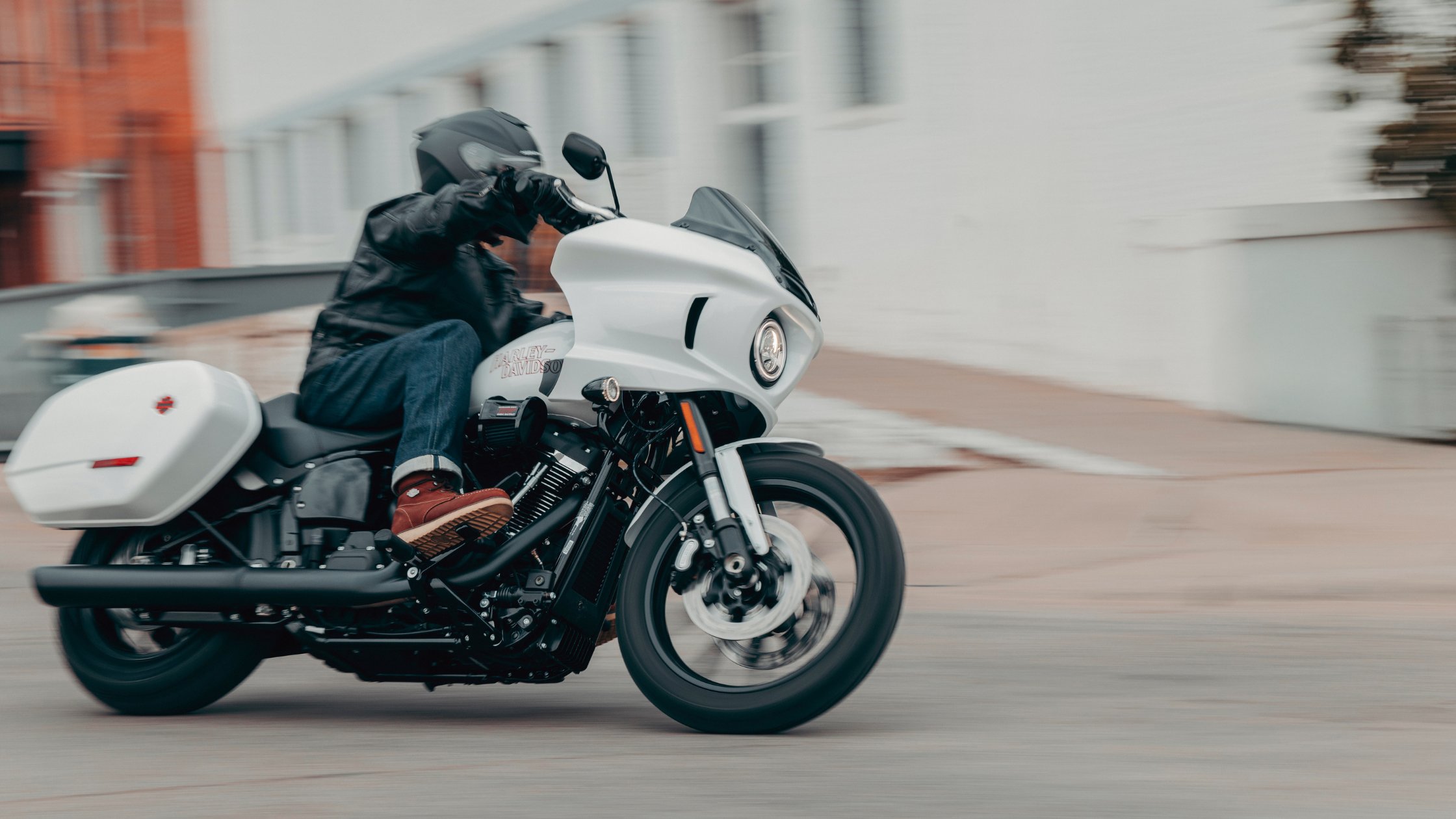 Rider turns a white 2026 Harley-Davidson® Low Rider® ST on an urban street in motion