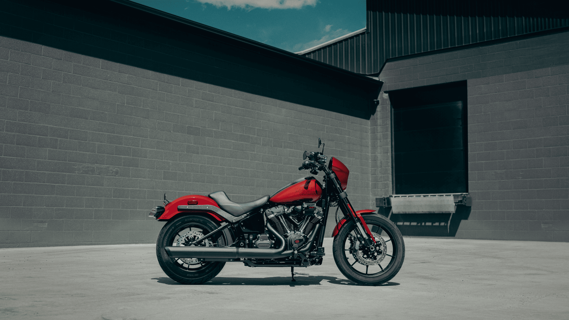 2025 H-D® Low Rider® S in vivid red finish parked against industrial gray wall background
