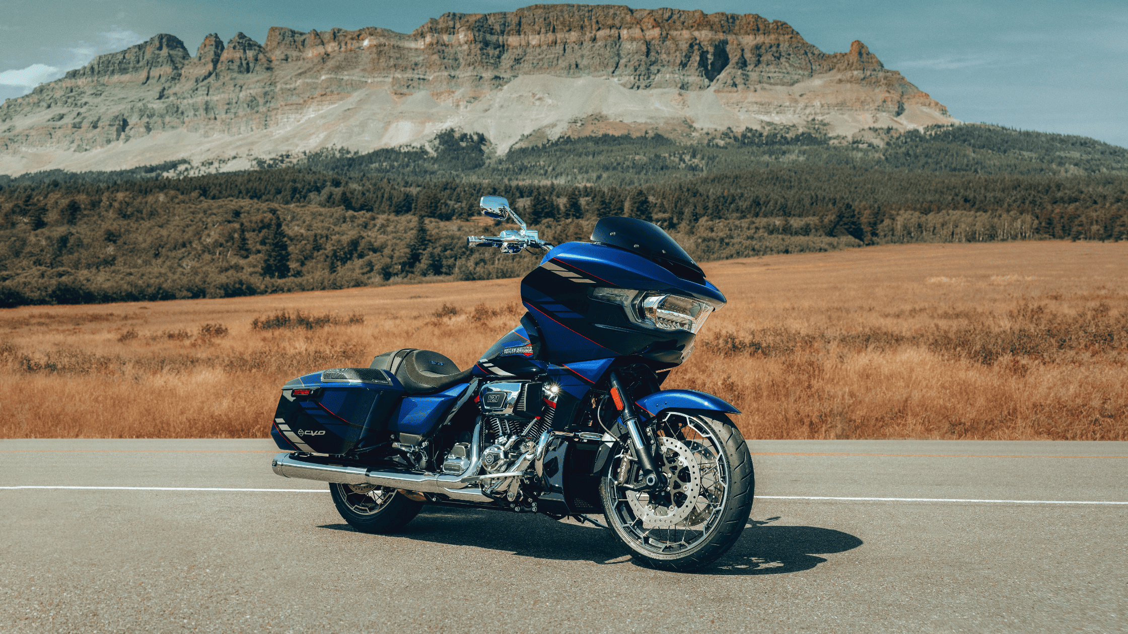 Parked 2025 Harley-Davidson CVO Road Glide in scenic valley with towering rocky mountains behind.